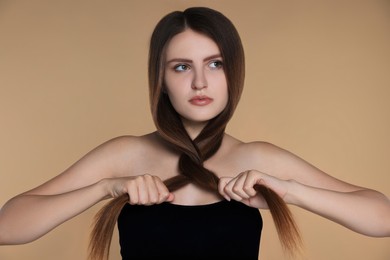 Photo of Young woman with strong healthy hair on beige background