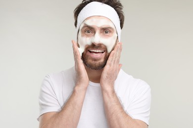 Photo of Man with headband washing his face on light grey background