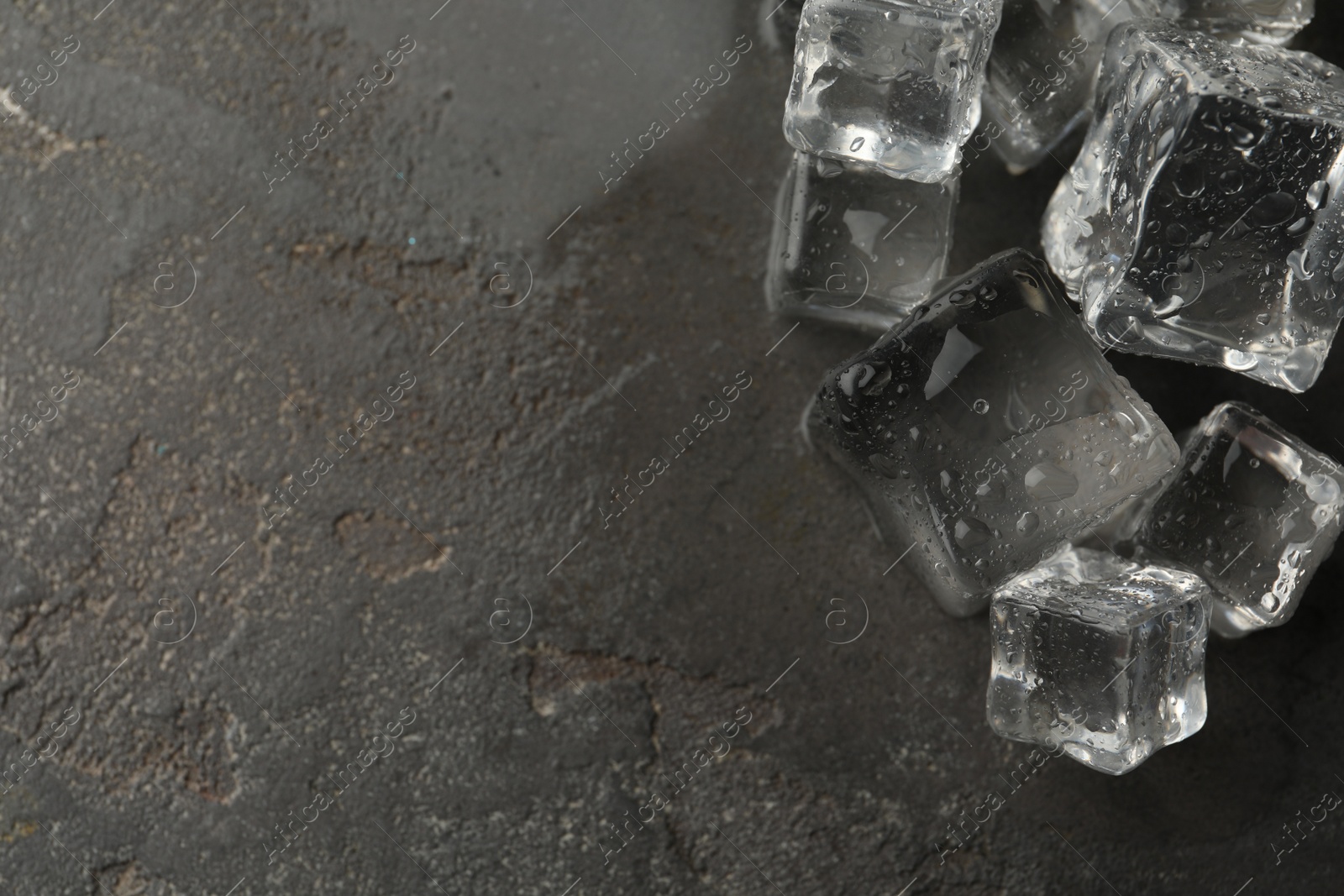 Photo of Crystal clear ice cubes with water drops on grey table, flat lay. Space for text