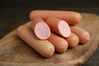 Photo of Whole and cut delicious boiled sausages on table, closeup