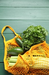 String bag with different vegetables on green wooden table, top view