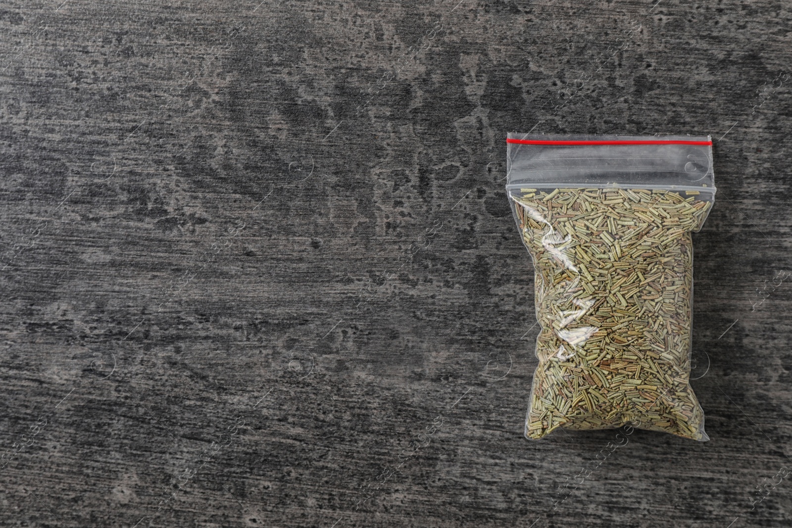 Photo of Plastic bag with spice on grey background, top view