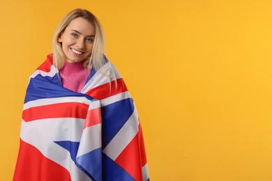 Photo of Happy woman with flag of United Kingdom on orange background, space for text
