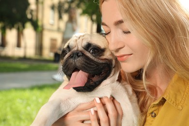 Photo of Woman with cute pug dog outdoors on sunny day, closeup. Animal adoption
