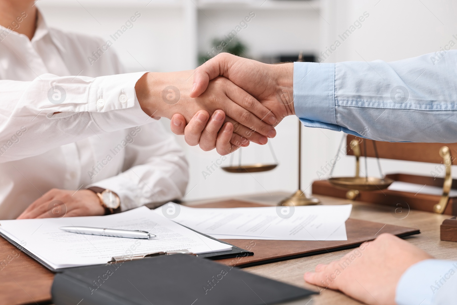 Photo of Lawyers shaking hands at table in office, closeup