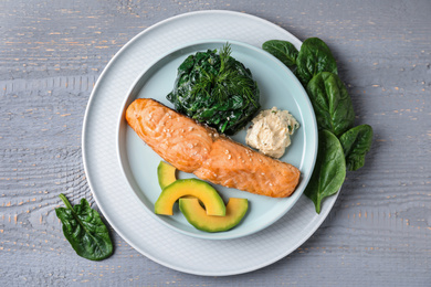 Photo of Tasty salmon with spinach and avocado on grey wooden table, flat lay