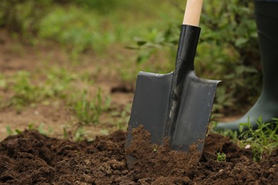 Photo of Worker in rubber boots with shovel outdoors, closeup. Gardening tool