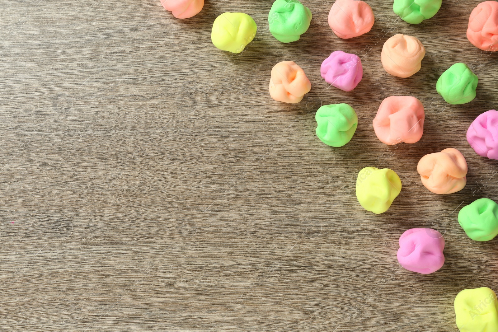 Photo of Different color play dough on wooden table, flat lay. Space for text