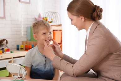 Photo of Speech therapist working with little boy in office