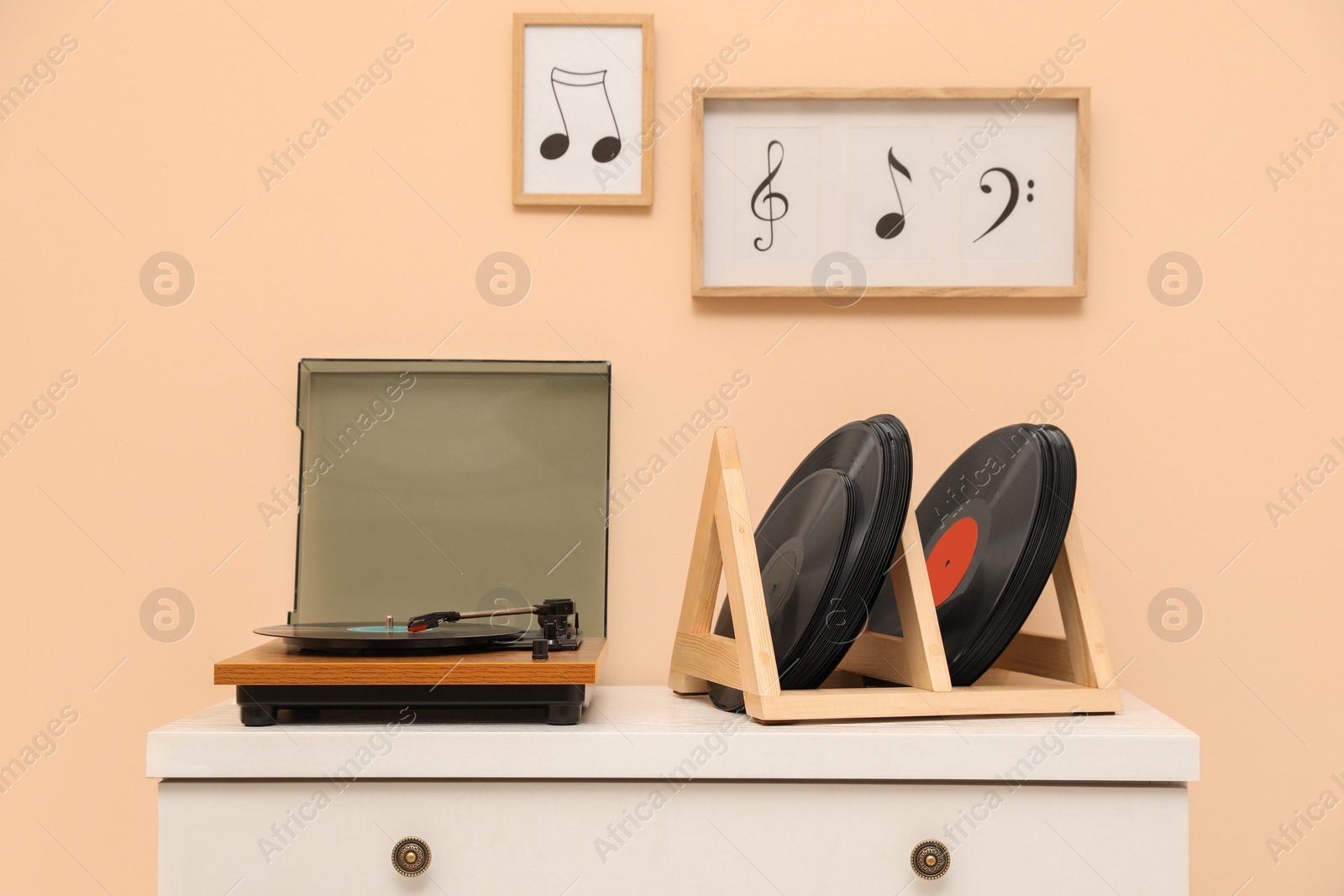 Photo of Vinyl records and player on white wooden drawer dresser near beige wall