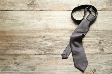 One necktie on light wooden table, top view. Space for text