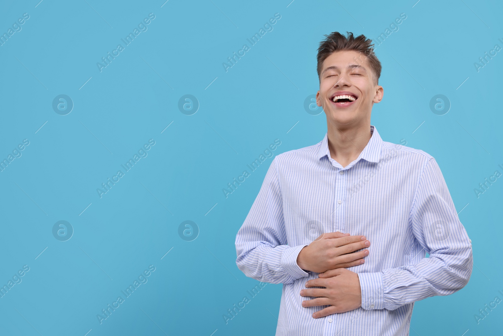 Photo of Young man laughing on light blue background. Space for text