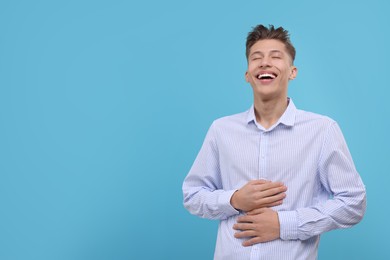 Photo of Young man laughing on light blue background. Space for text