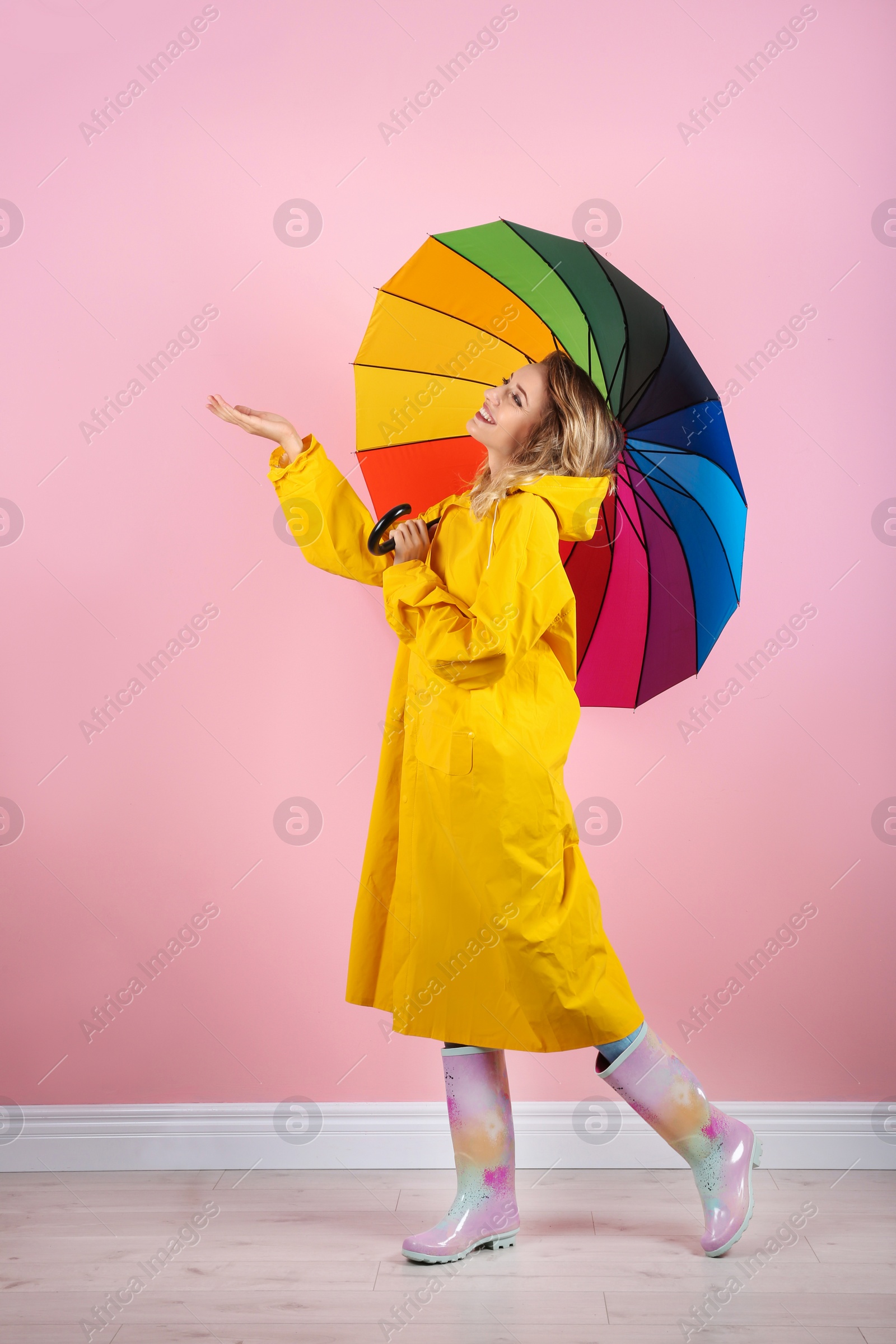 Photo of Woman with rainbow umbrella near color wall