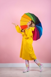 Woman with rainbow umbrella near color wall