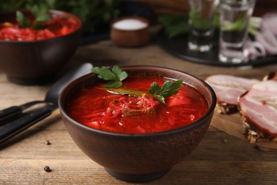 Photo of Stylish brown clay bowl with Ukrainian borsch served on wooden table