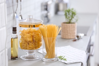 Photo of Raw pasta on light grey table in modern kitchen