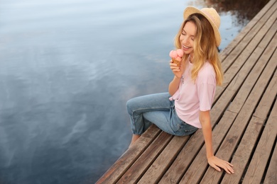 Happy young woman with delicious ice cream in waffle cone outdoors. Space for text