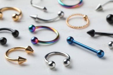 Photo of Stylish piercing jewelry on white table, closeup