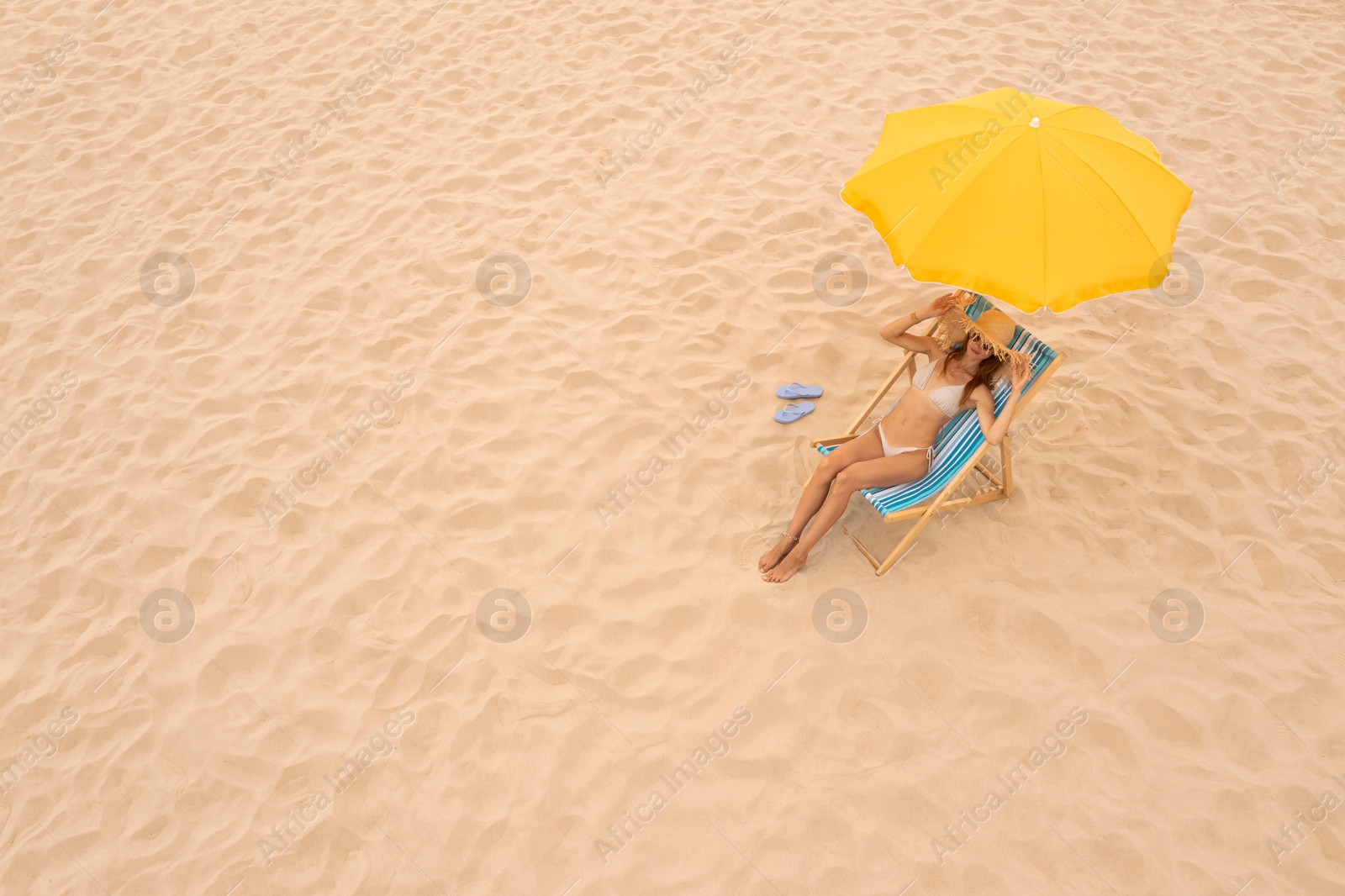 Image of Woman resting in sunbed under yellow beach umbrella at sandy coast, space for text