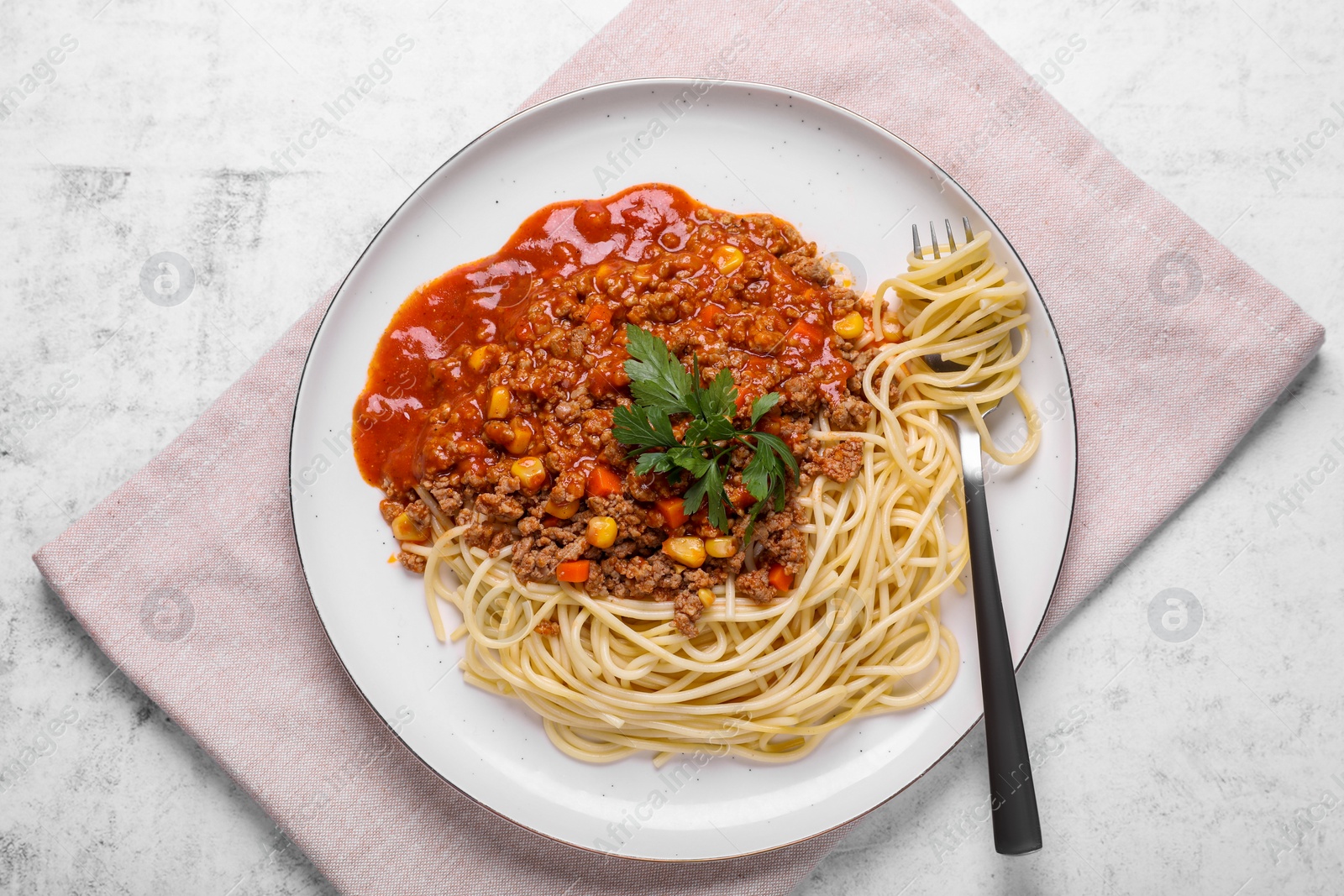 Photo of Tasty dish with fried minced meat, spaghetti, carrot and corn served on white textured table, top view