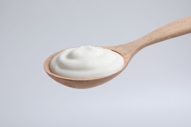 Photo of Delicious natural yogurt in spoon on light background