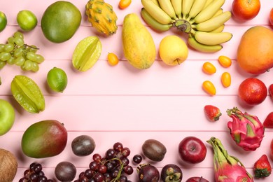 Frame of different delicious exotic fruits on pink wooden table, flat lay. Space for text