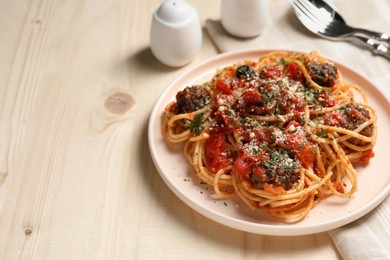 Photo of Delicious pasta with meatballs and tomato sauce served on wooden table. Space for text
