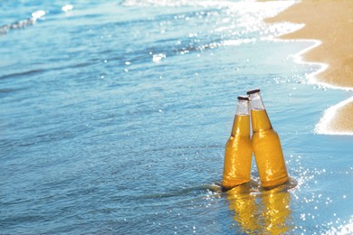 Photo of Bottles of cold beer in sea water, space for text