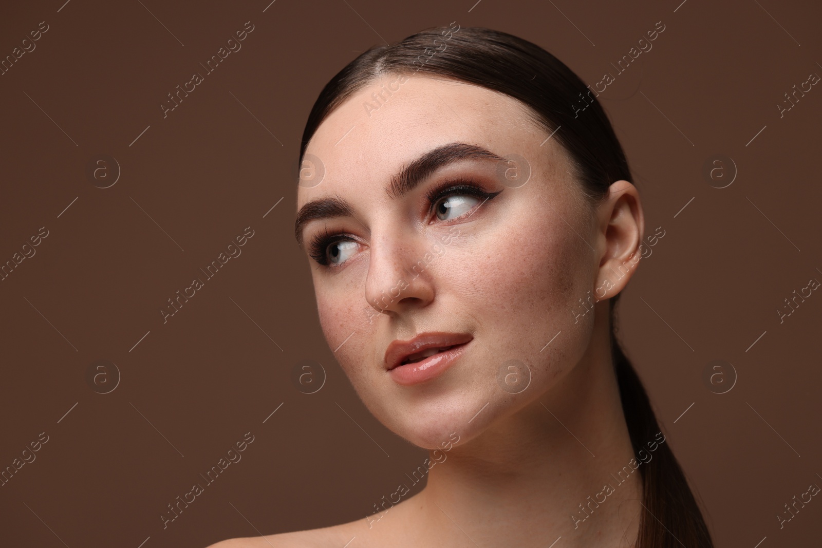 Photo of Portrait of beautiful woman with fake freckles on brown background