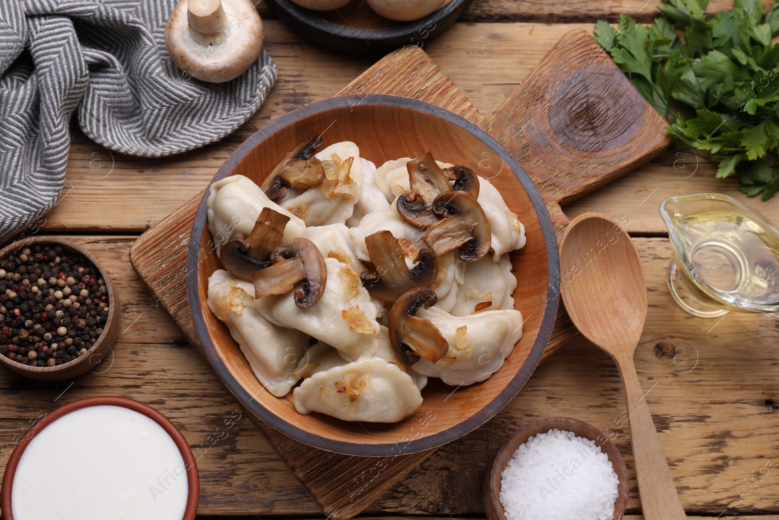 Photo of Delicious dumplings (varenyky) with potatoes, onion and mushrooms served on wooden table, flat lay