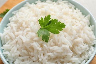 Bowl of delicious rice with parsley on table, closeup