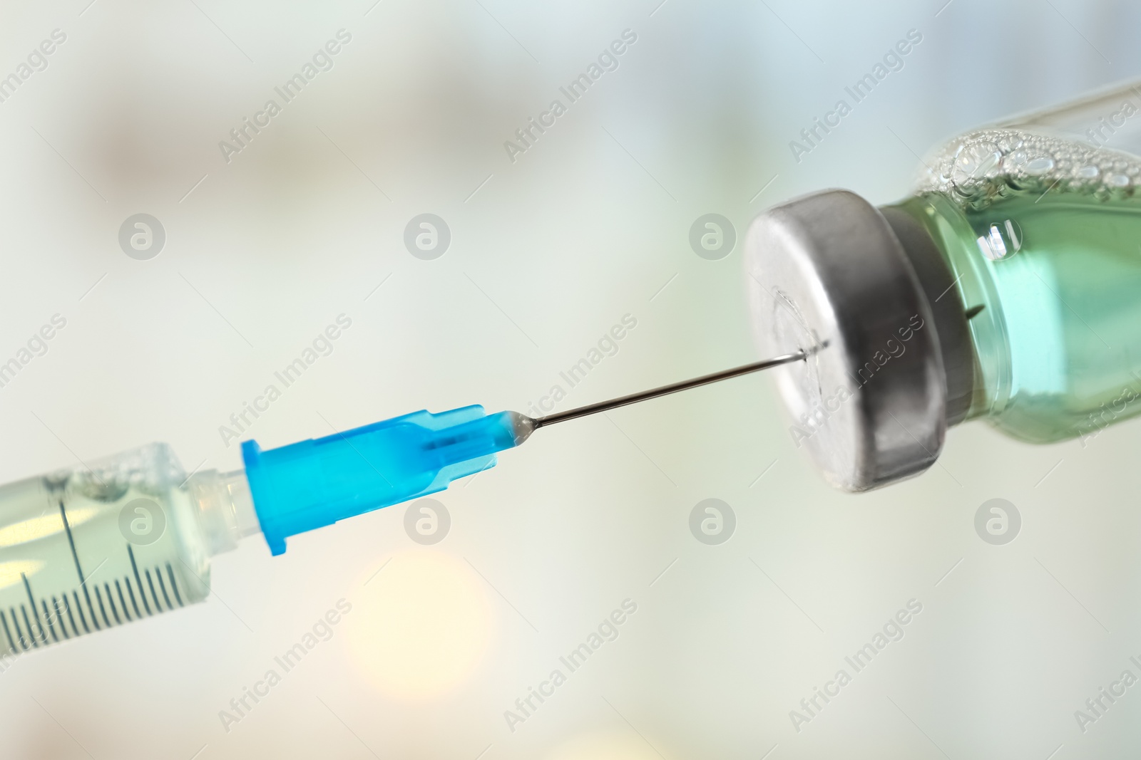 Photo of Filling syringe with vaccine on blurred background, closeup