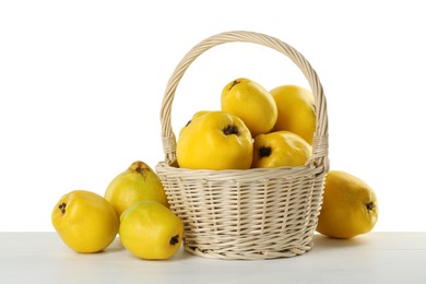 Photo of Basket with delicious fresh ripe quinces on light wooden table against white background