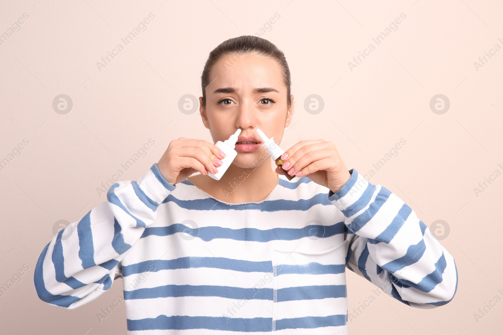 Photo of Woman using nasal sprays on beige background