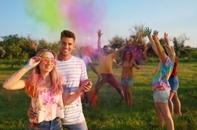 Photo of Happy friends with colorful powder dyes outdoors. Holi festival celebration