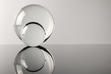 Transparent glass balls on mirror surface against light background. Space for text