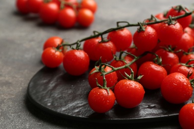 Photo of Fresh ripe cherry tomatoes with water drops on grey table, closeup