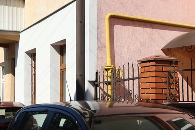 Photo of Yellow gas pipe on pink wall outdoors