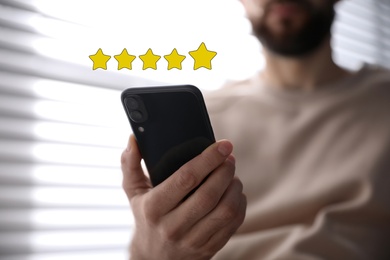 Man leaving review online via smartphone indoors, closeup. Five stars over gadget