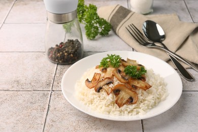 Photo of Delicious rice with parsley and mushrooms served on tiled table, space for text