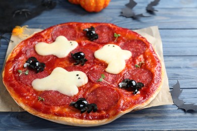 Photo of Cute Halloween pizza with ghosts and spiders served on blue wooden table, closeup