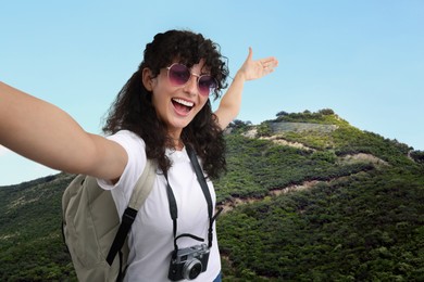 Image of Beautiful woman in sunglasses with camera taking selfie in mountains