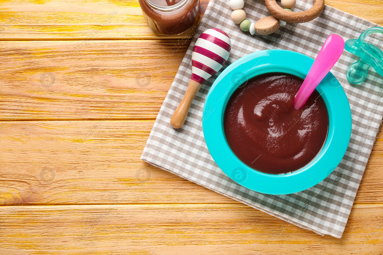 Photo of Flat lay composition with bowl of healthy baby food on wooden table. Space for text