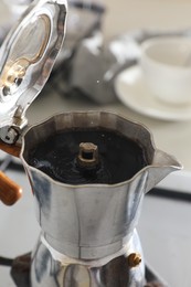 Photo of Brewing aromatic coffee in moka pot on stove indoors, closeup