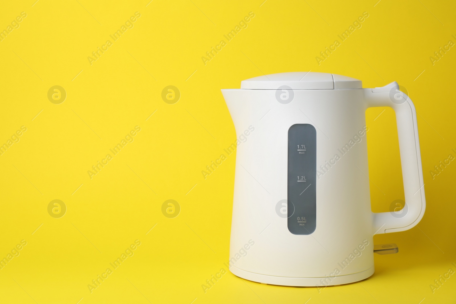 Photo of Modern electric kettle on yellow background, space for text