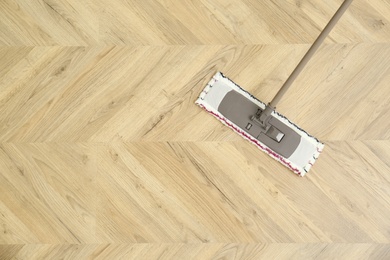 Photo of Cleaning of wooden floor with mop, top view. Space for text