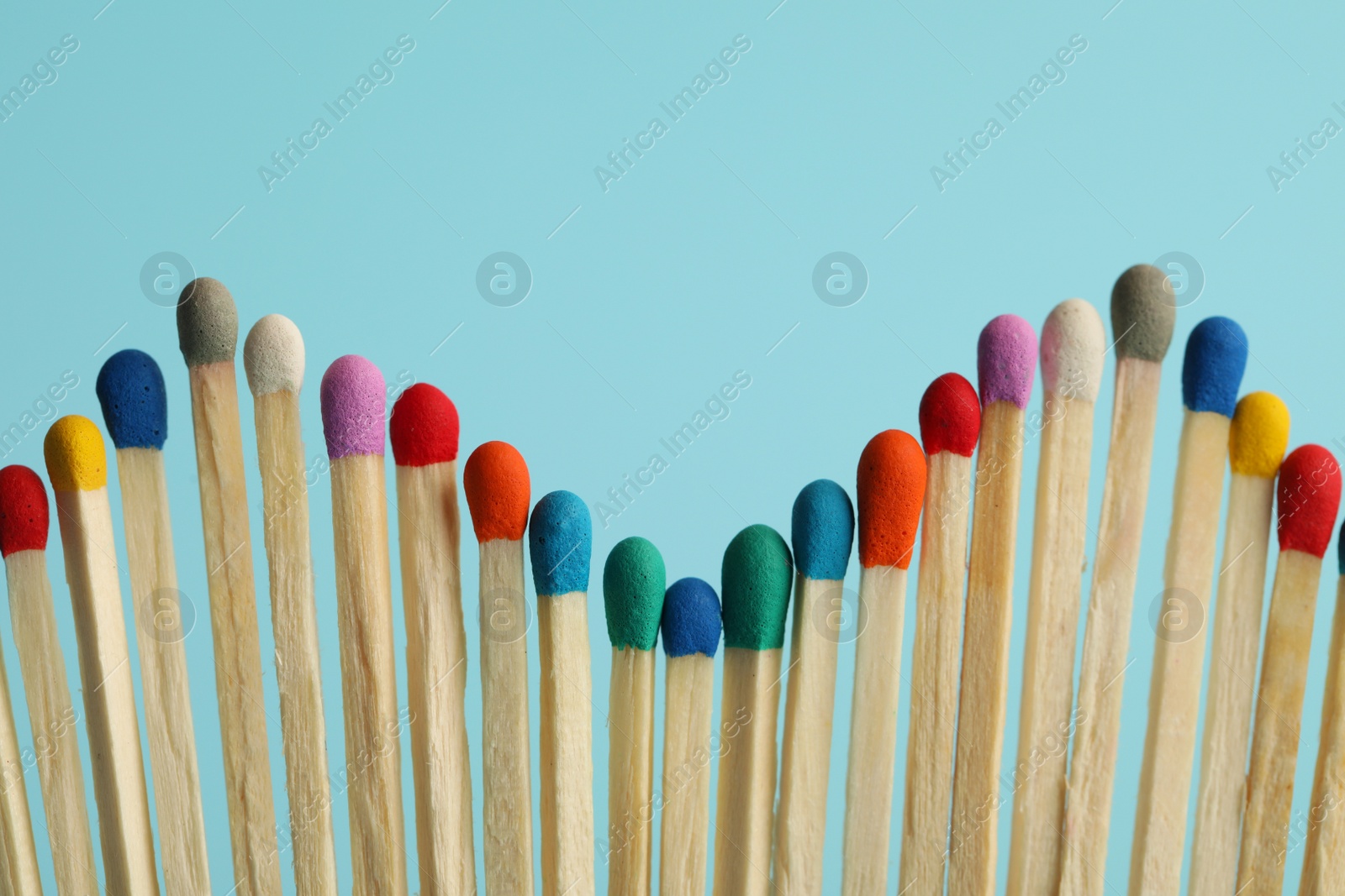 Photo of Matches with colorful heads on light blue background, closeup