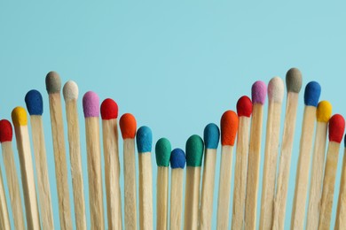 Photo of Matches with colorful heads on light blue background, closeup