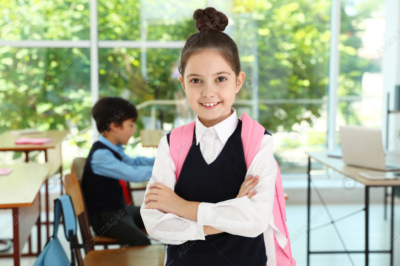 Photo of Girl wearing school uniform with backpack in classroom